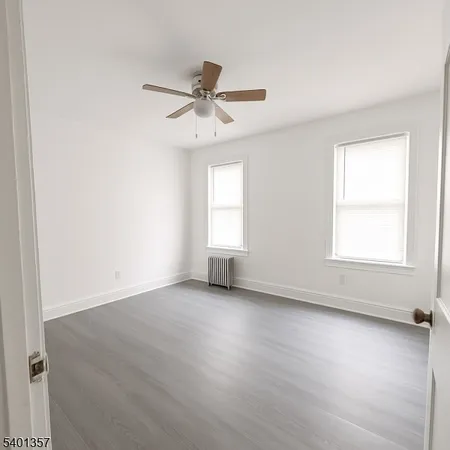 an empty room with wooden floor fan and windows