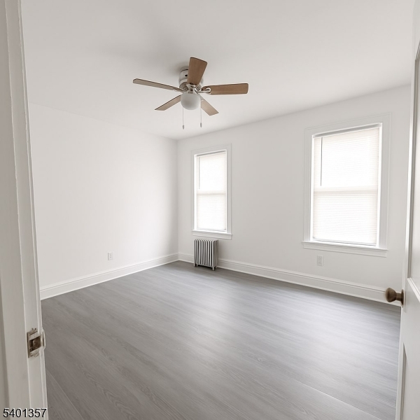 237 Wainwright Street Newark, NJ 07112 - Photo 2 of 5 an empty room with wooden floor fan and windows