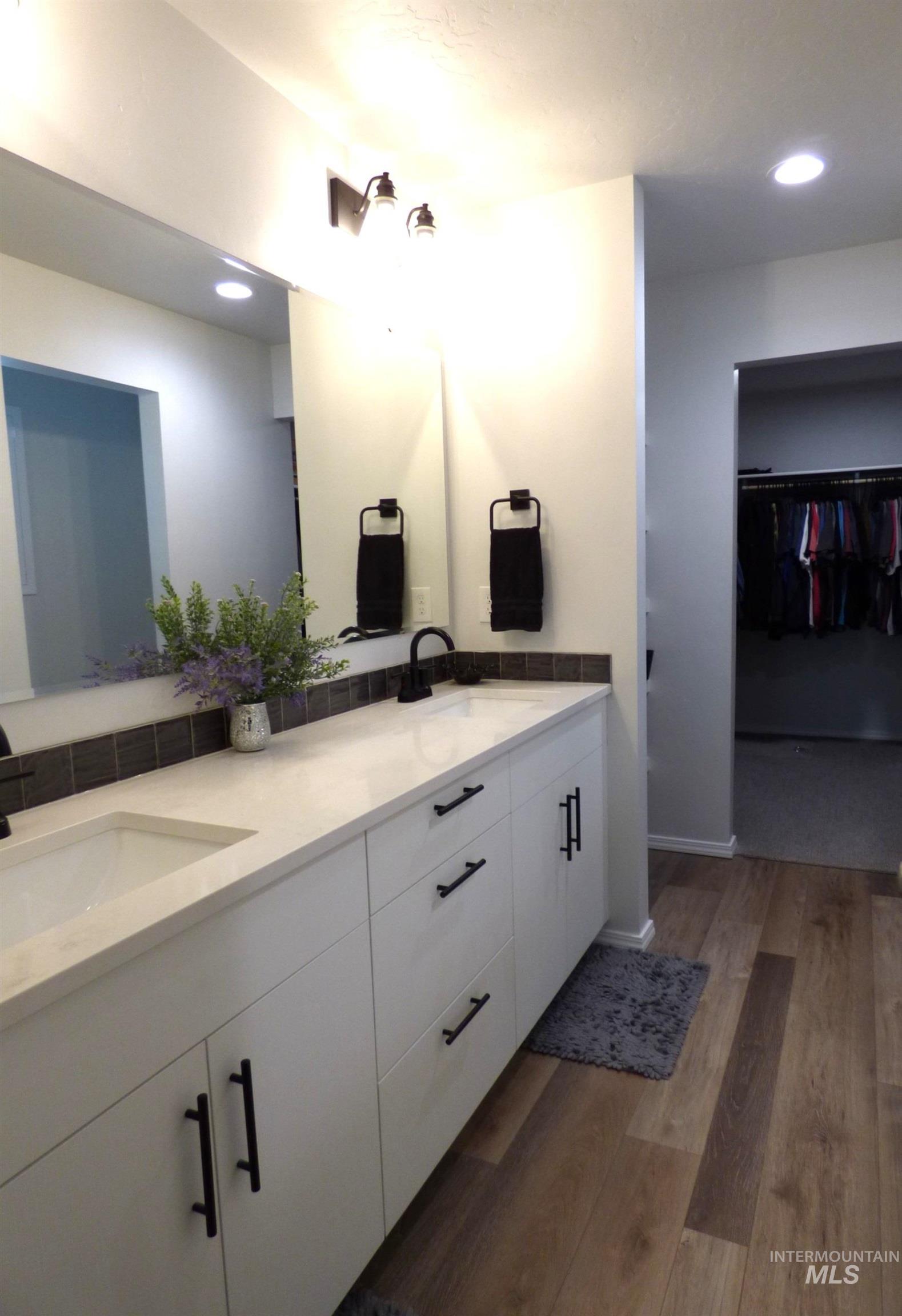 2708 East Buckaroo Drive Kuna, ID 83634 - Photo 19 of 48 Vanity with dual integrated sinks, white cabinetry, matte black hardware, and wood-finish flooring