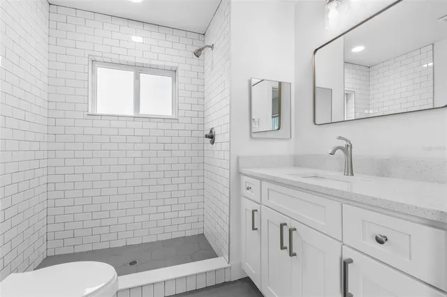 a bathroom with a toilet sink vanity and mirror