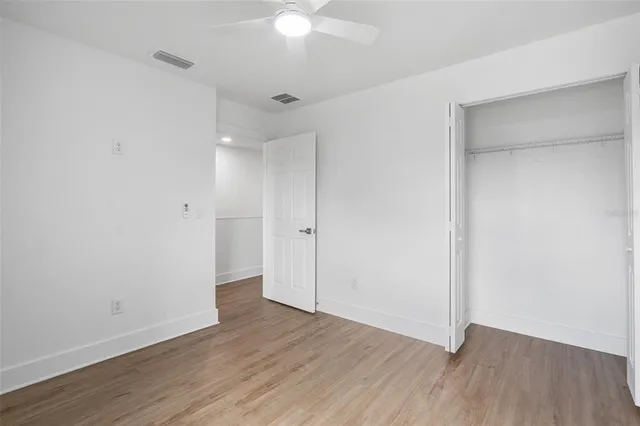 an empty room with wooden floor and a ceiling fan