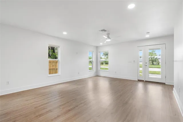 a view of an empty room with wooden floor and a window