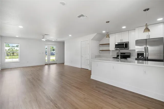 a view of kitchen with cabinets stainless steel appliances and wooden floor