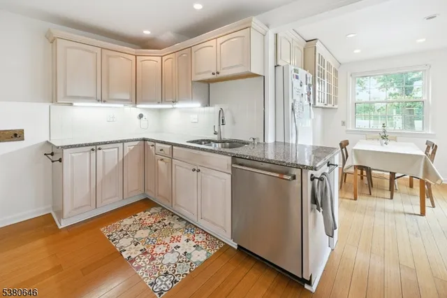 a kitchen with stainless steel appliances granite countertop a stove a sink dishwasher and a refrigerator with wooden floor