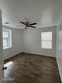 a view of an empty room with a window and wooden floor