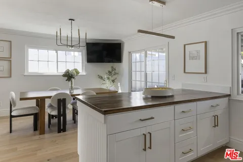 a kitchen with stainless steel appliances granite countertop a sink a stove a dining table and chairs with wooden floor