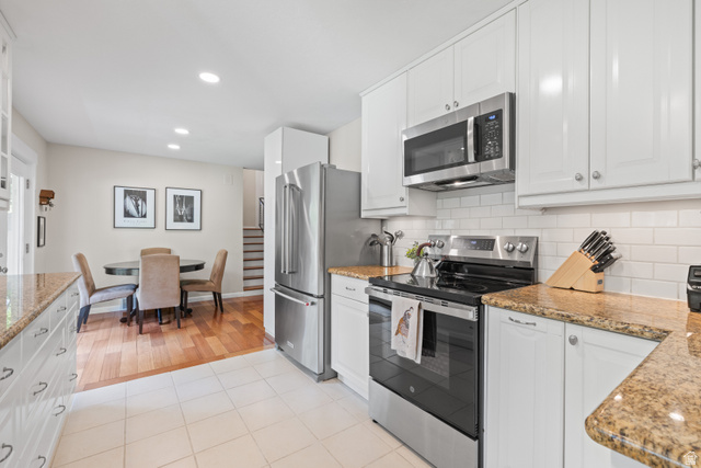 3320 Cherokee Lane Provo, UT 84604 - Photo 15 of 52 Kitchen featuring white shaker-style cabinetry, granite countertops, stainless steel appliances, and a white subway tile backsplash
