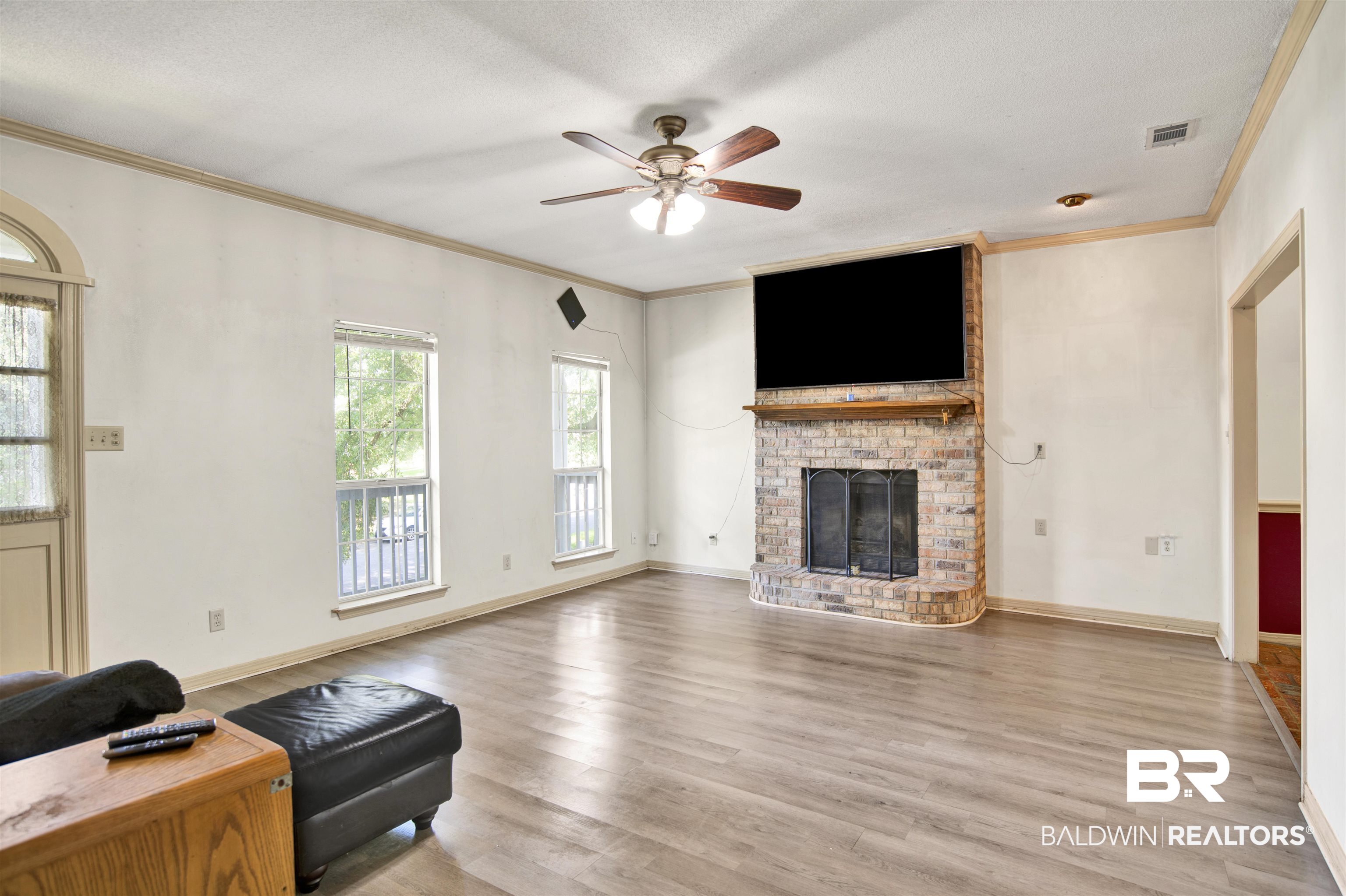 3412 Peyton Court Mobile, AL 36695 - Photo 8 of 27 Living area with ornamental molding, ceiling fan, wood finished floors, a brick fireplace, and baseboards