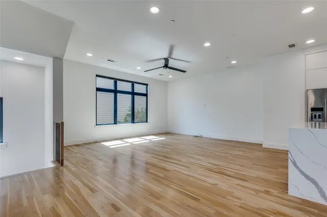 a view of an empty room with wooden floor ceiling fan