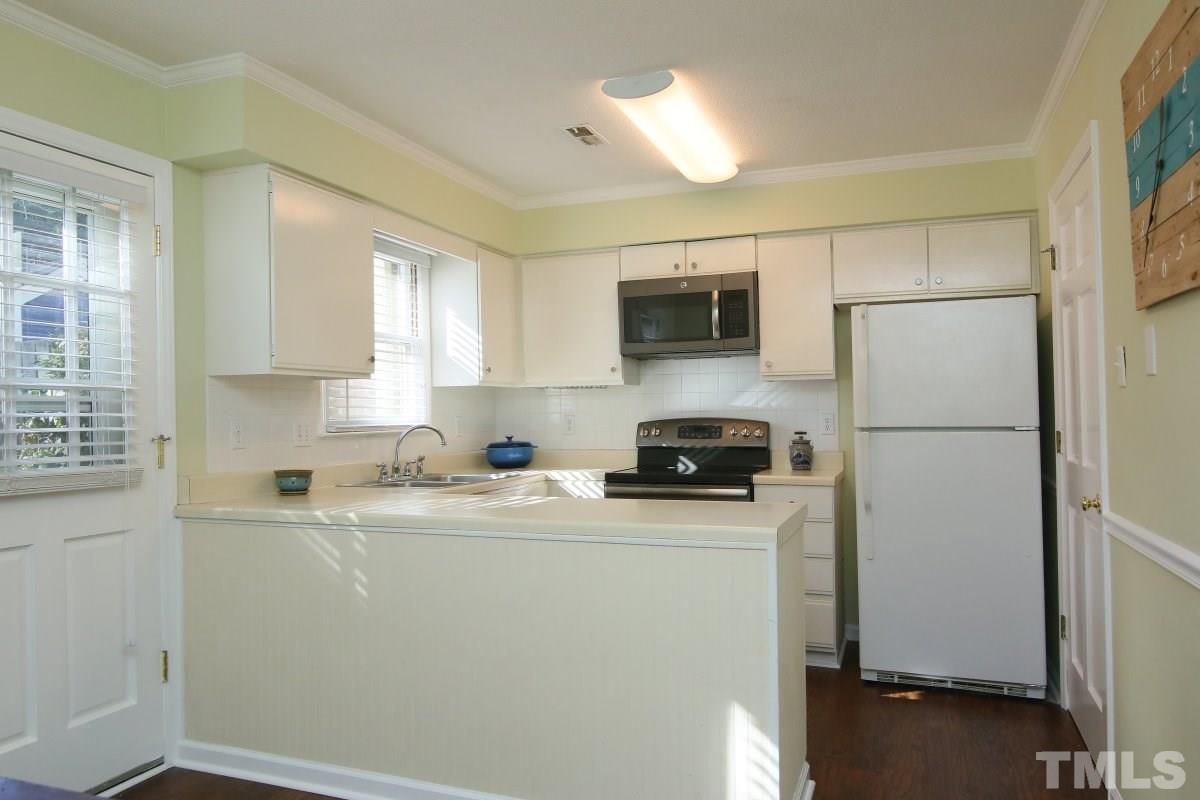 5649 Hamstead Crossing Raleigh, NC 27612 - Photo 8 of 25 a kitchen with a refrigerator a stove a sink a window and cabinets
