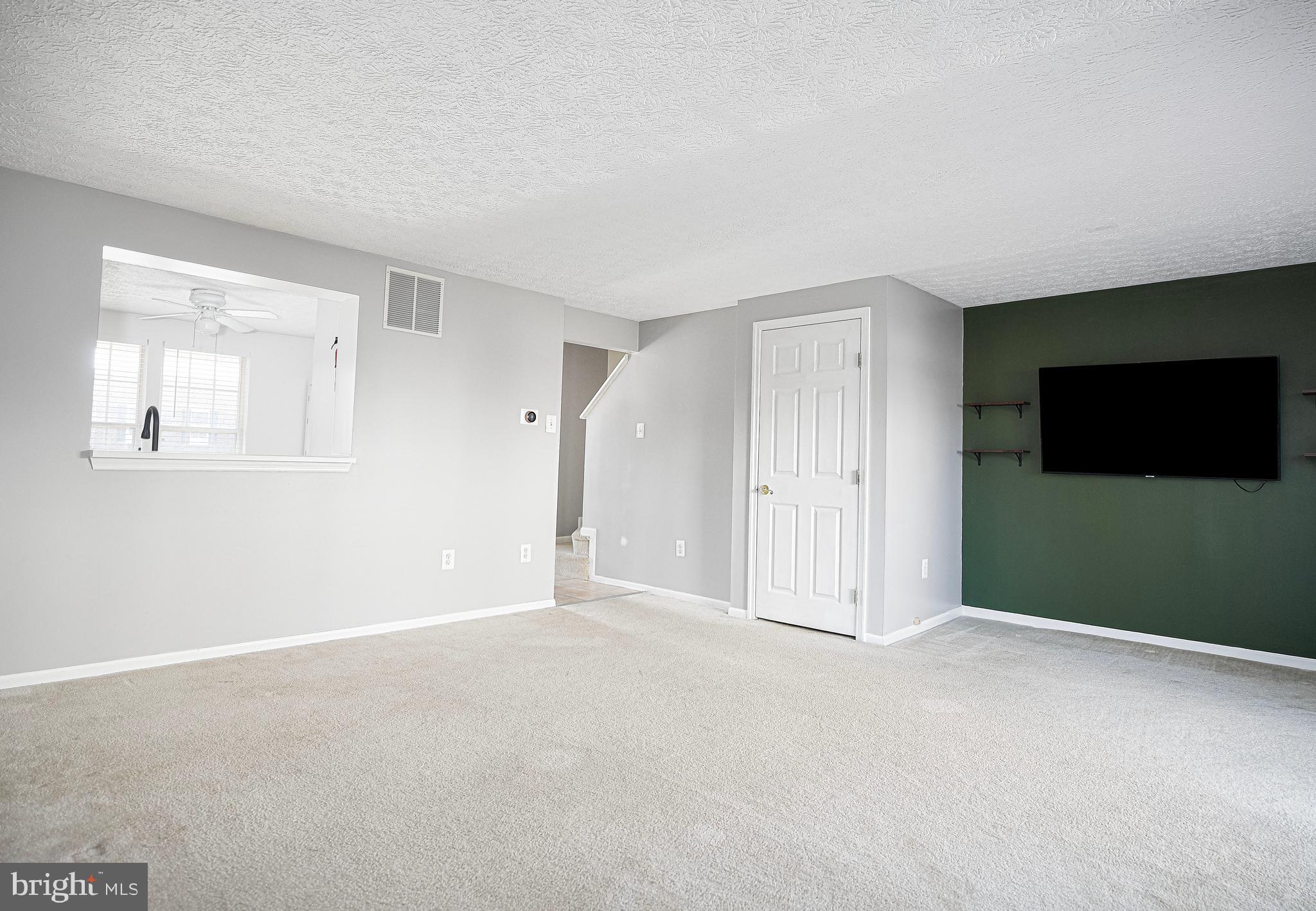 3702 Timahoe Circle Baltimore, MD 21236 - Photo 4 of 34 a view of an empty room with a flat screen tv and kitchen view