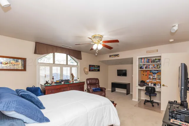 an empty room with chandelier fan and windows