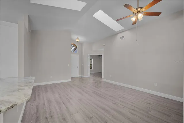 an empty room with wooden floor and a ceiling fan