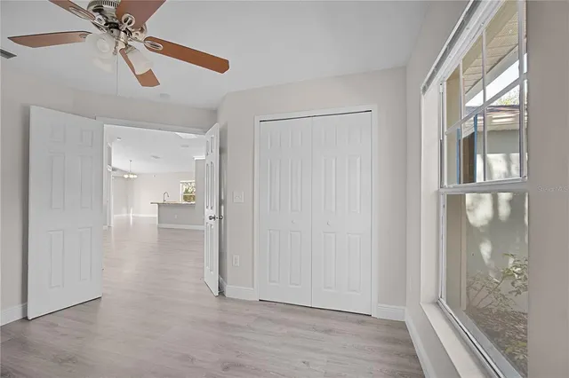a view of a hallway with a chandelier fan and windows