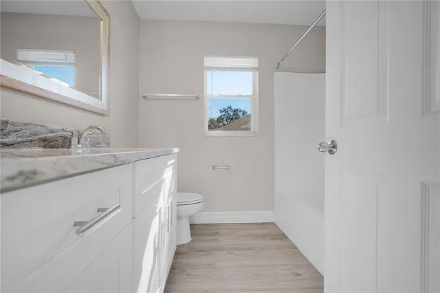 a bathroom with a granite countertop sink a toilet and a mirror