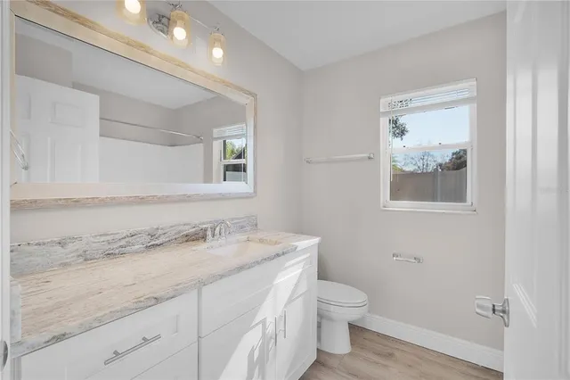 a bathroom with a granite countertop toilet sink and mirror