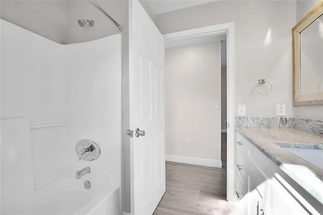 a bathroom with a granite countertop sink a mirror and a bathtub