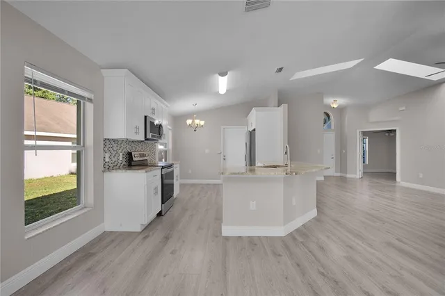 a large kitchen with white cabinets and wooden floor