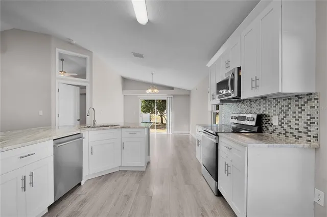 a large kitchen with cabinets a sink a window and stainless steel appliances