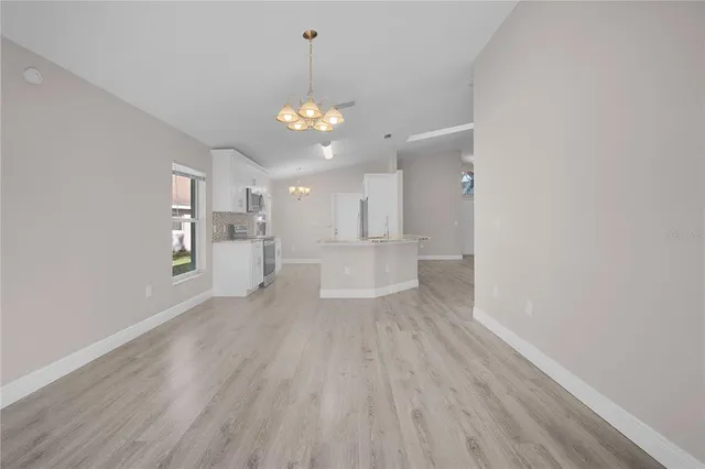 a view of an empty room and a kitchen