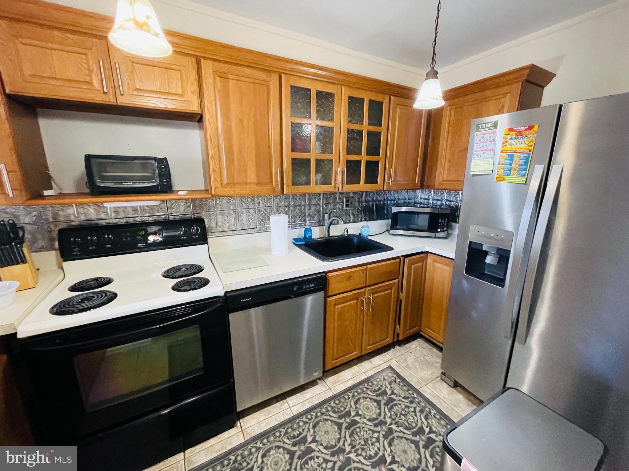 46 Township Line Road, Unit 215 Elkins Park, PA 19027 - Photo 6 of 17 a kitchen with stainless steel appliances a stove a sink and a microwave