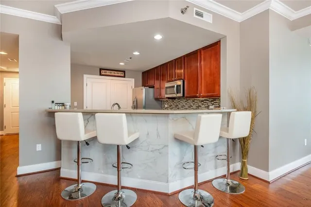 a view of kitchen with granite countertop wooden floor cabinets and chairs