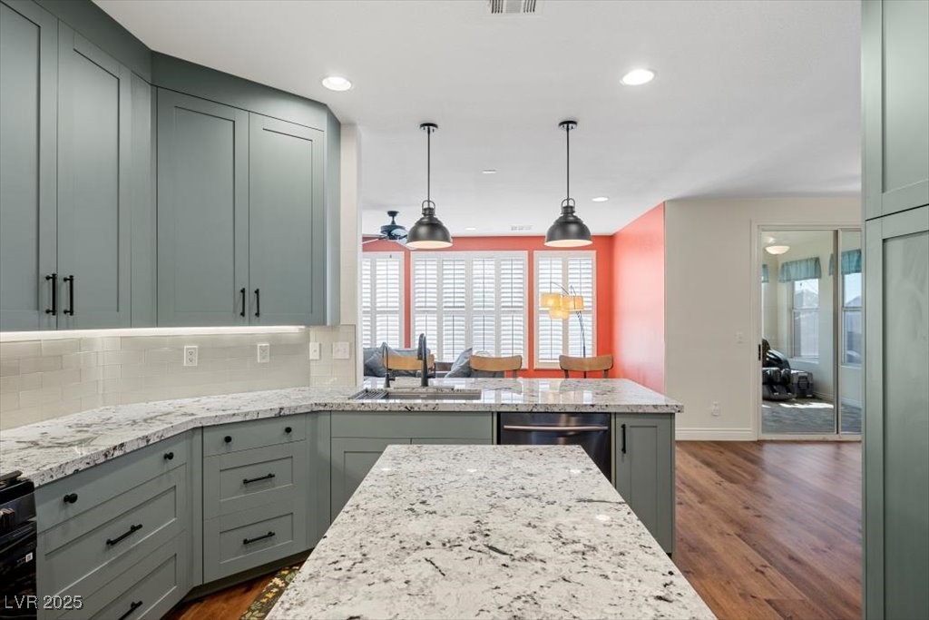 249 Cinnamon Ridge Way Henderson, NV 89015 - Photo 8 of 76 Kitchen featuring stainless steel dishwasher, dark wood-style floors, tasteful backsplash, light stone counters, and recessed lighting