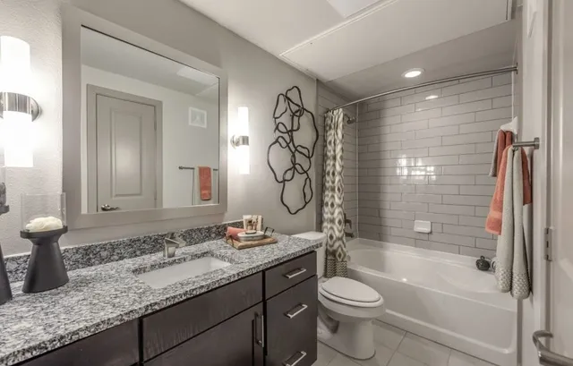 a bathroom with a granite countertop sink a mirror and shower