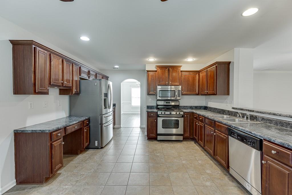 926 Red Wolf Court Dacula, GA 30019 - Photo 15 of 47 a kitchen with stainless steel appliances granite countertop a stove top oven a sink and a refrigerator