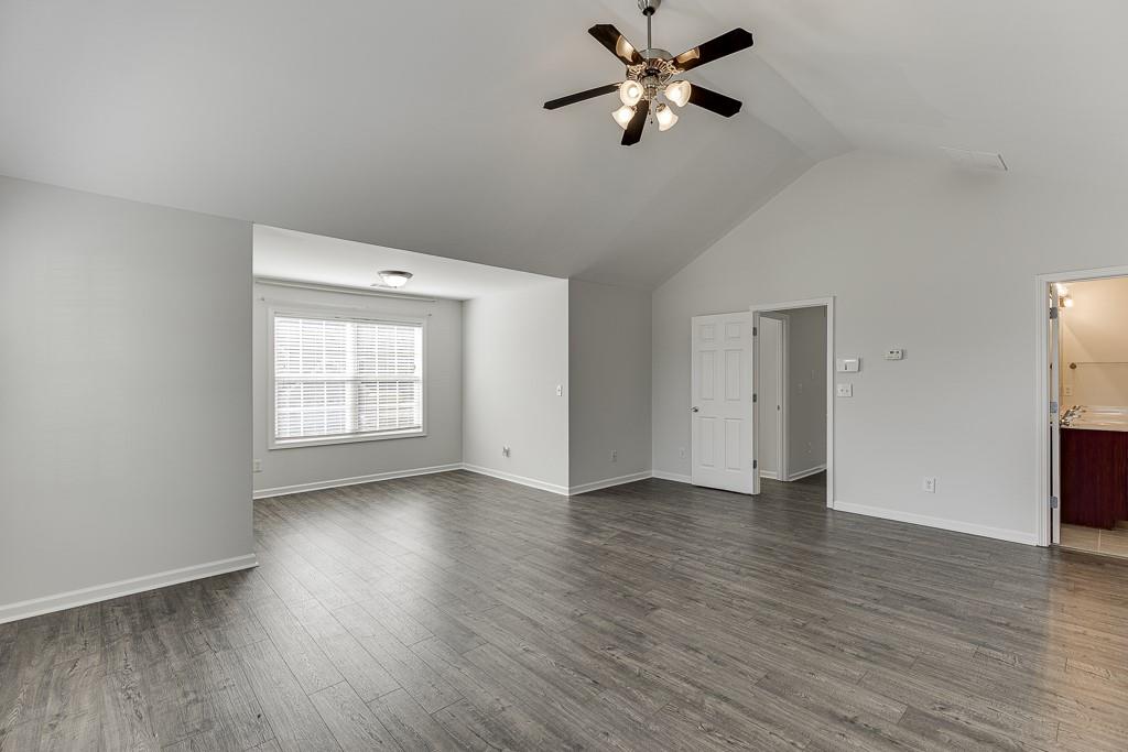 926 Red Wolf Court Dacula, GA 30019 - Photo 23 of 47 an empty room with wooden floor chandelier fan and windows