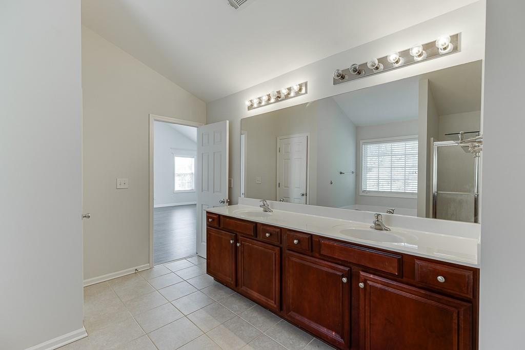 926 Red Wolf Court Dacula, GA 30019 - Photo 27 of 47 a spacious bathroom with a double vanity sink a large mirror and a bathtub