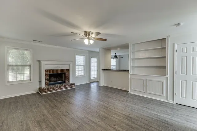 an empty room with wooden floor fireplace and windows