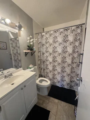 a bathroom with a granite countertop sink toilet and shower
