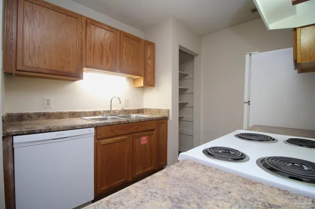 a kitchen with stainless steel appliances granite countertop a sink and a stove with white countertops