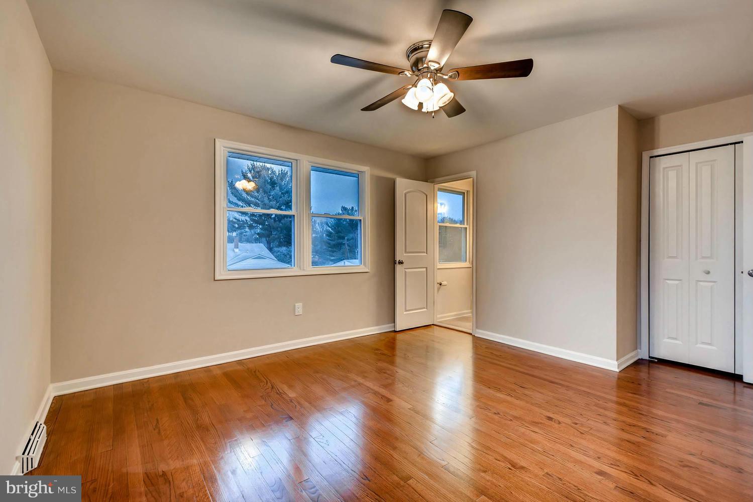 4515 Tapscott Road Pikesville, MD 21208 - Photo 13 of 28 an empty room with wooden floor chandelier fan and windows