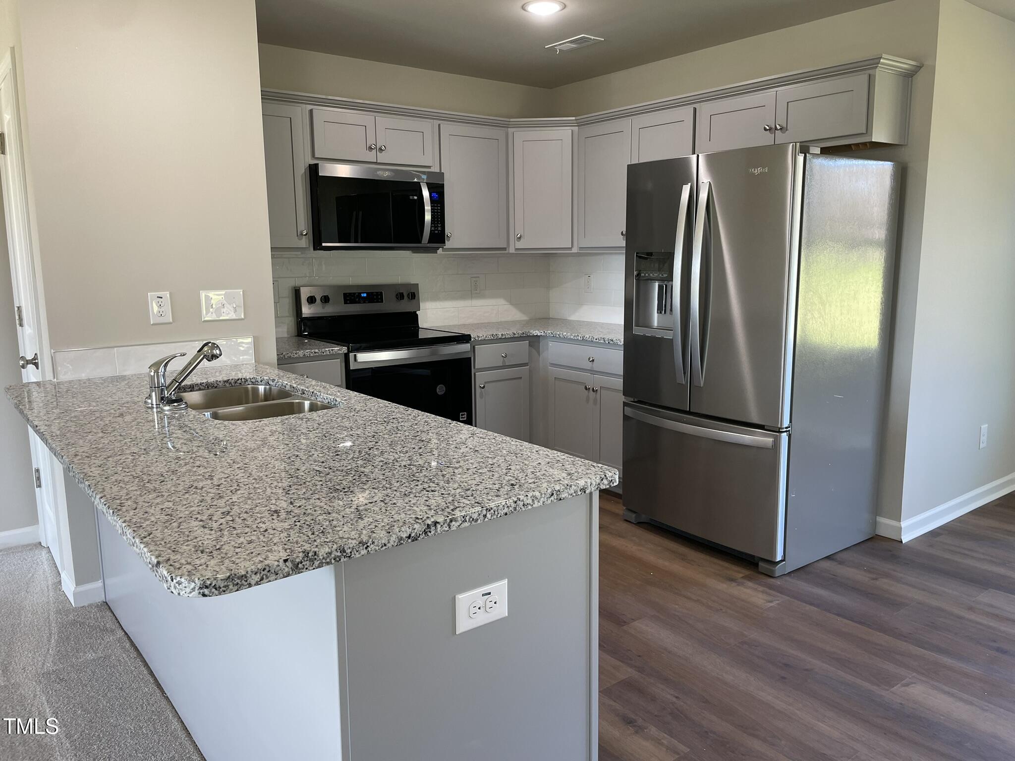 181 Pate Landing Drive Selma, NC 27576 - Photo 3 of 15 a kitchen with granite countertop a refrigerator and a stove top oven