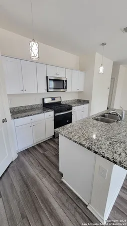 a kitchen with kitchen island granite countertop a sink cabinets and stainless steel appliances