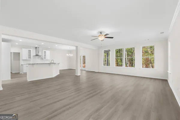 a view of an empty room with a kitchen and wooden floor