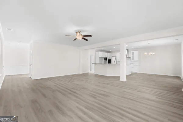 a view of empty room with wooden floor and kitchen view
