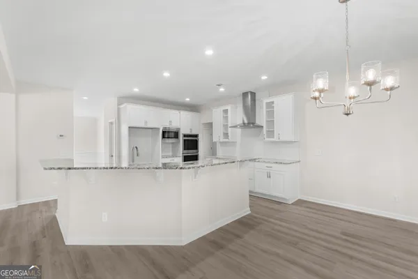 a large kitchen with stainless steel appliances kitchen island a large counter top and wooden floors