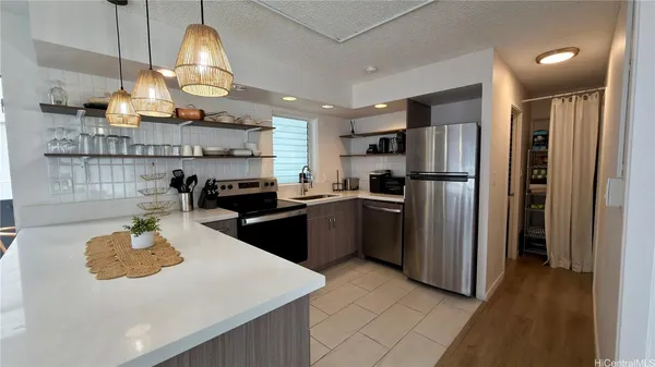 a kitchen with stainless steel appliances granite countertop a sink a stove a refrigerator cabinets and chairs