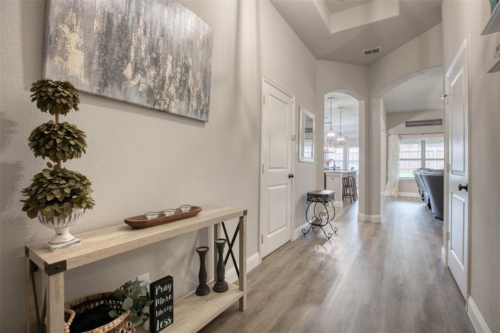 211 Rees Avenue Godley, TX 76044 - Photo 3 of 18 a hallway with a dining table wooden floor and a chandelier