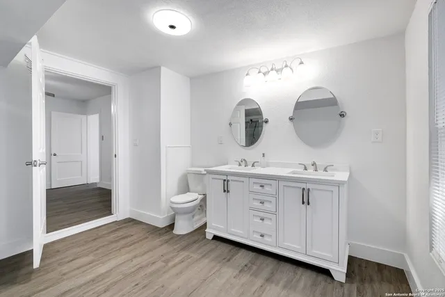 a bathroom with a double vanity sink mirror and toilet