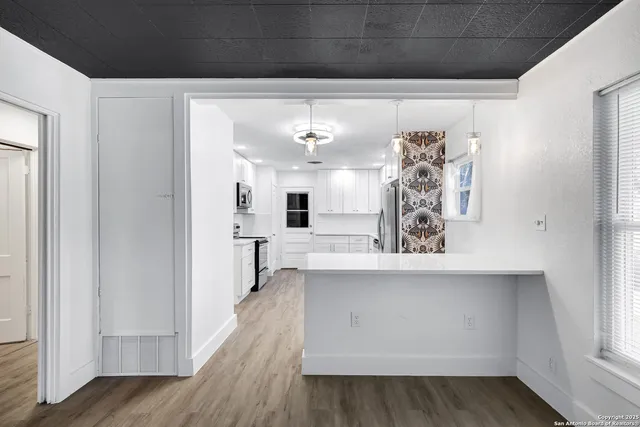 a view of a hallway with wooden floor and chandelier