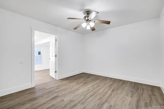 an empty room with wooden floor and fan