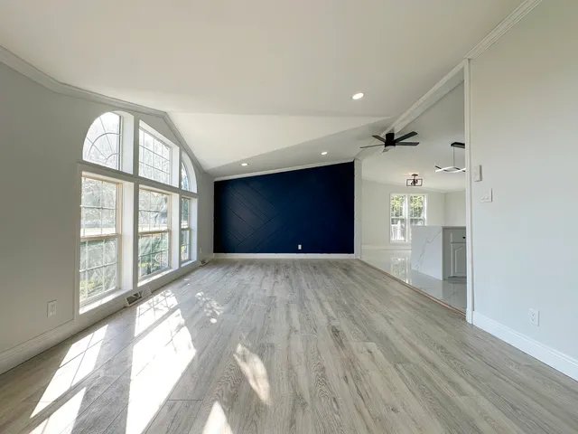 a view of empty room with wooden floor and fan