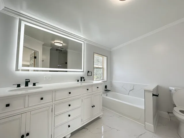 a bathroom with a double vanity sink mirror and bathtub