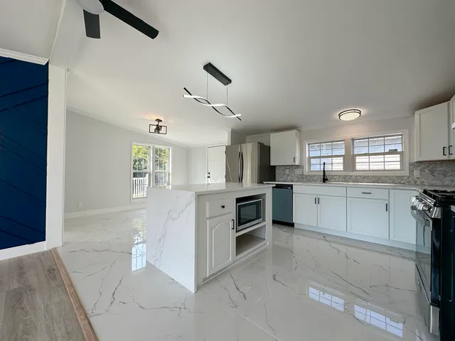 a large white kitchen with white cabinets and stainless steel appliances