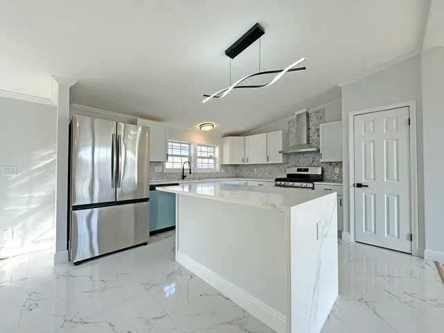 a kitchen with stainless steel appliances granite countertop a refrigerator a sink a stove and white cabinets