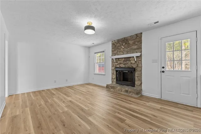 an empty room with windows and fireplace